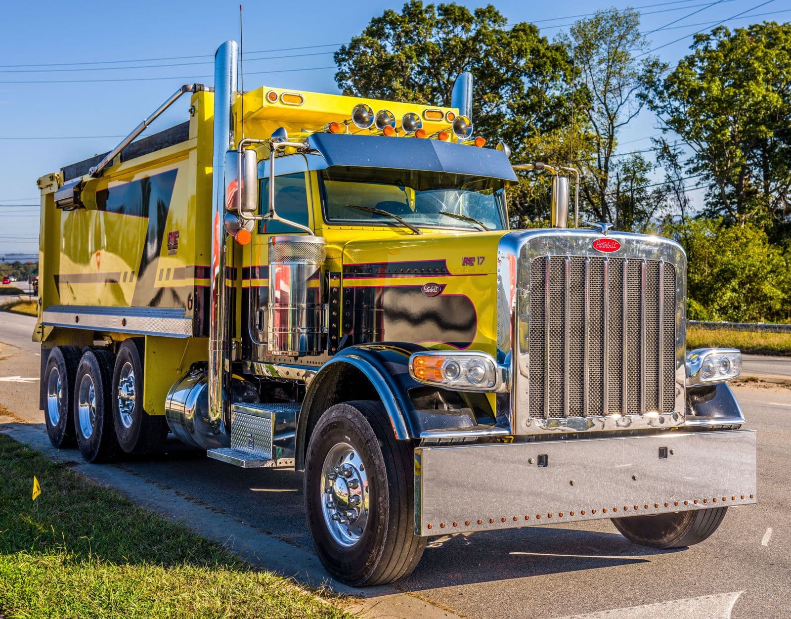 Bright yellow dump truck driving on a sunny road highlights transport and construction utility.